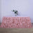 Pink ruffled table skirt with floral centerpiece and glasses on a table.