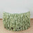 Round table with green ruffled table skirt on a plain background.