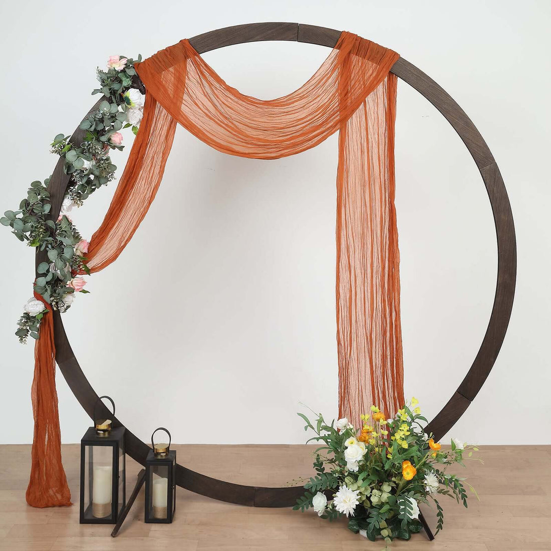 Circular display frame with draped fabric, flowers, and lanterns.