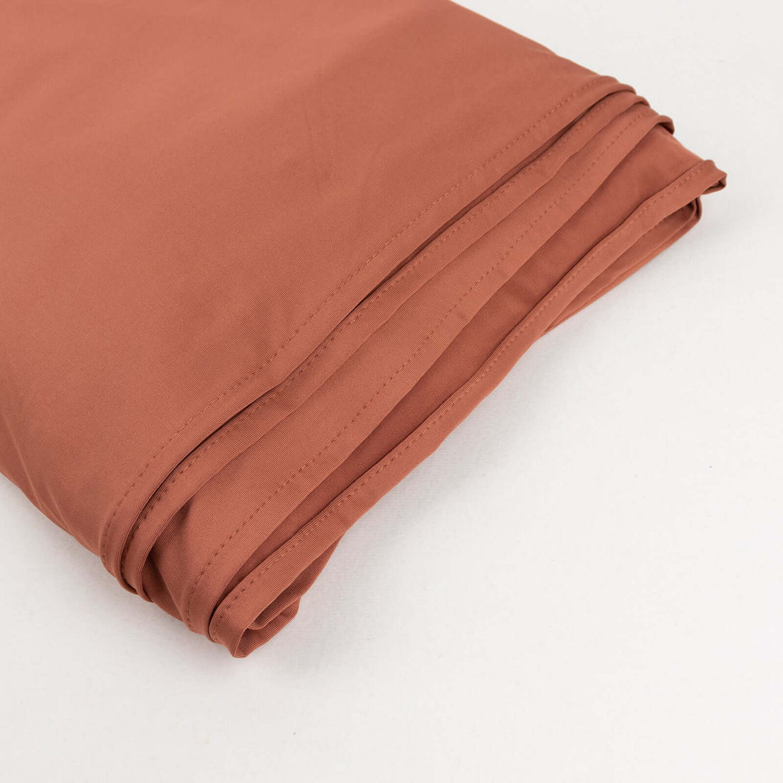 Folded rust-colored fabric on a plain background.