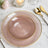 Elegant pink dinner plate with gold rim on a marble table setting.