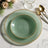 Elegant green dinnerware set with gold rim details on a marble surface.
