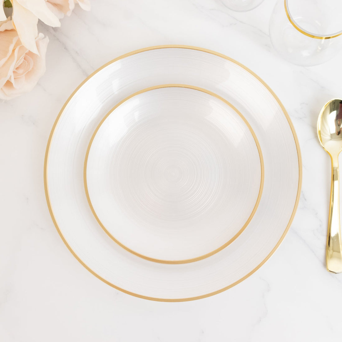 Elegant white dinner plates with gold rim on a marble surface.