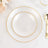Elegant white dinner plates with gold rim on a marble surface.