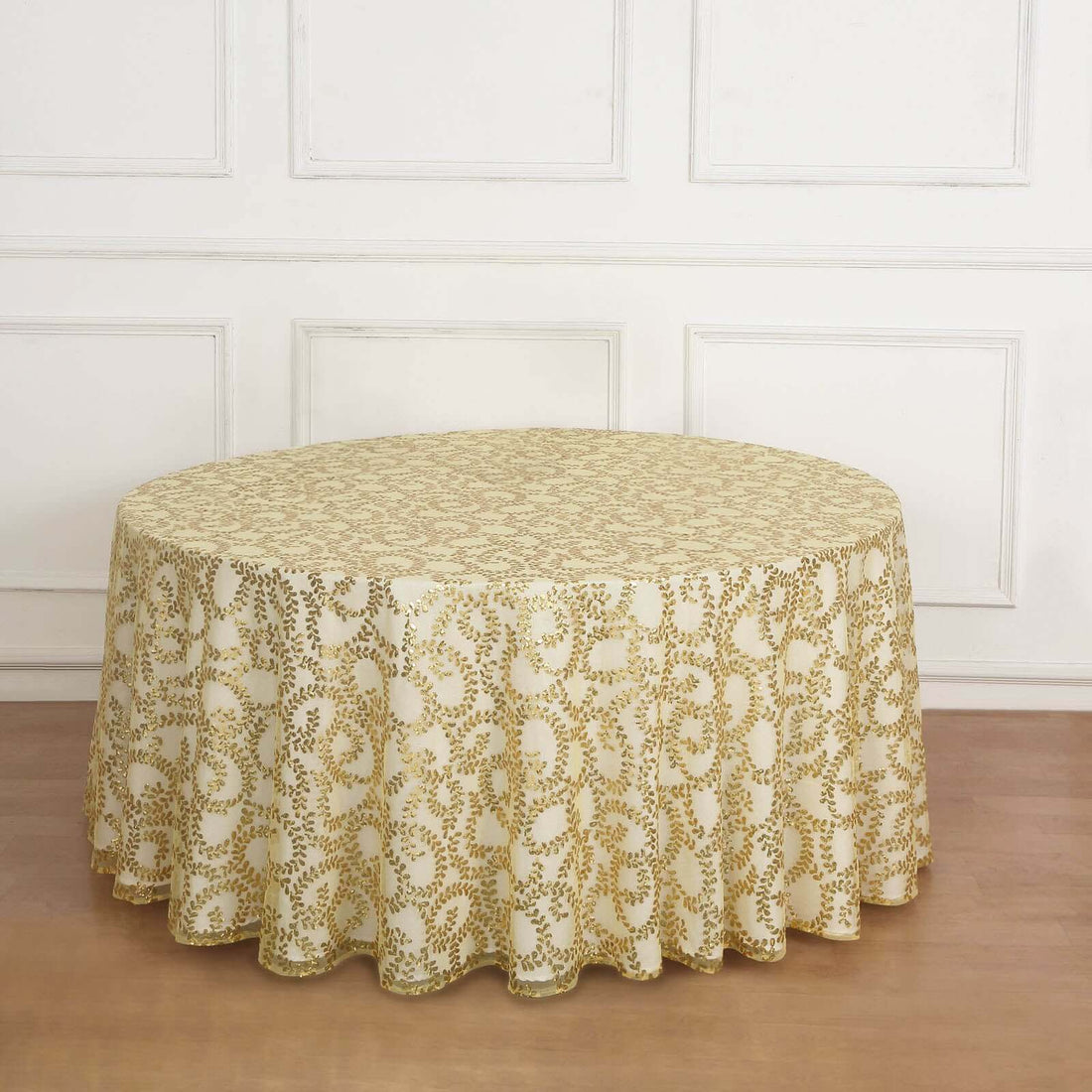 Round gold-patterned tablecloth on a wooden floor.