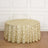 Round gold-patterned tablecloth on a wooden floor.