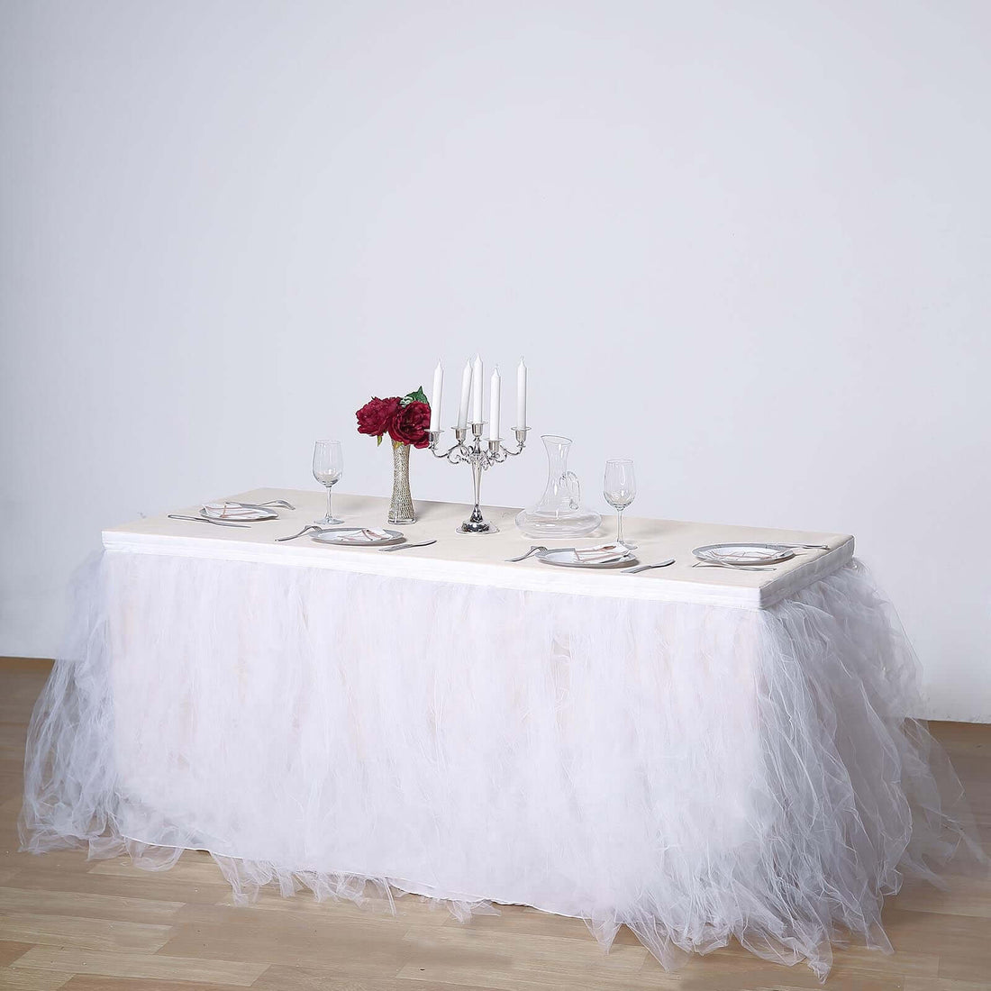 Elegant dining table set with white tulle skirt and floral centerpiece.