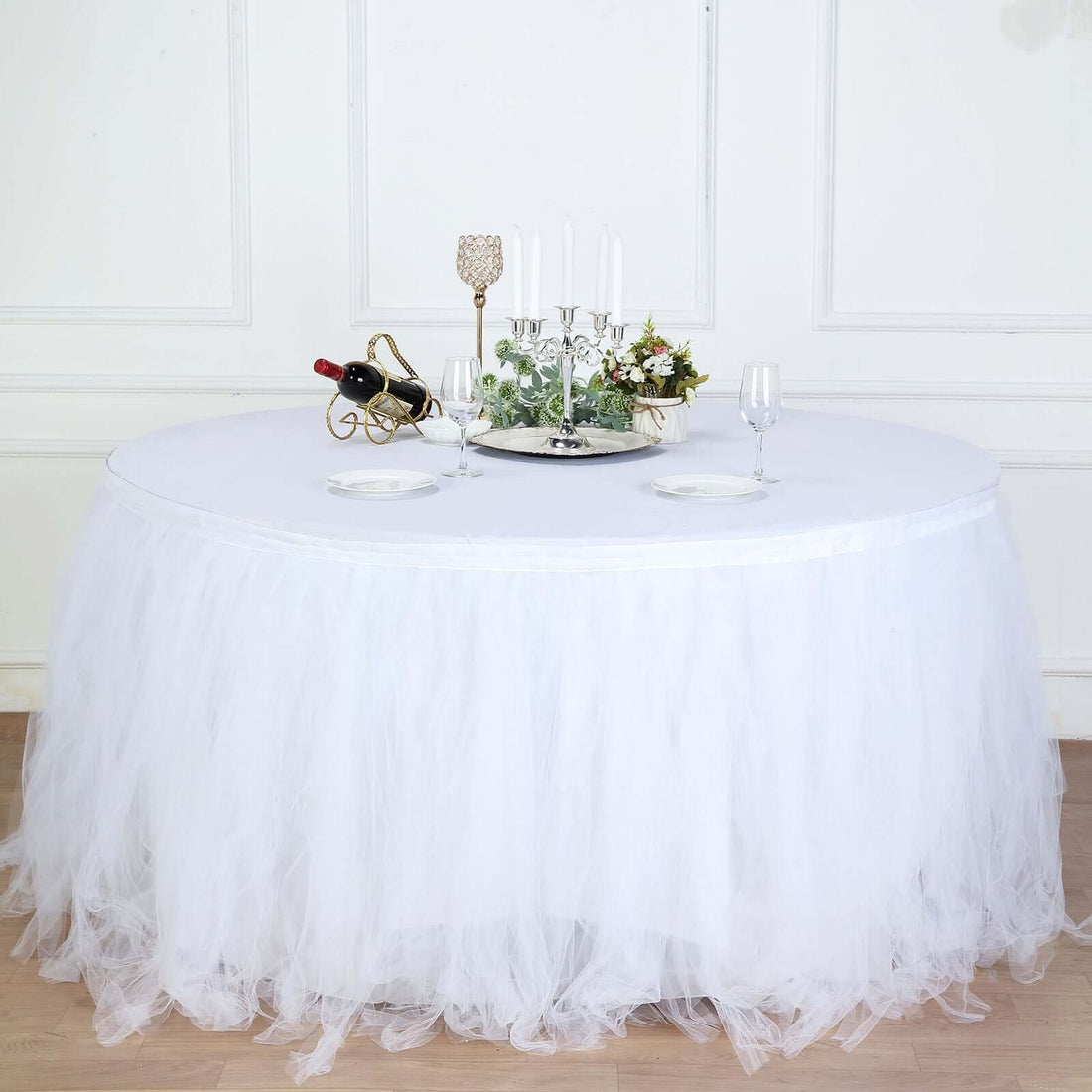 Round table with white tulle skirt and elegant centerpiece.