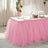 Pink tulle table skirt draping over a white table in a decorated setting.