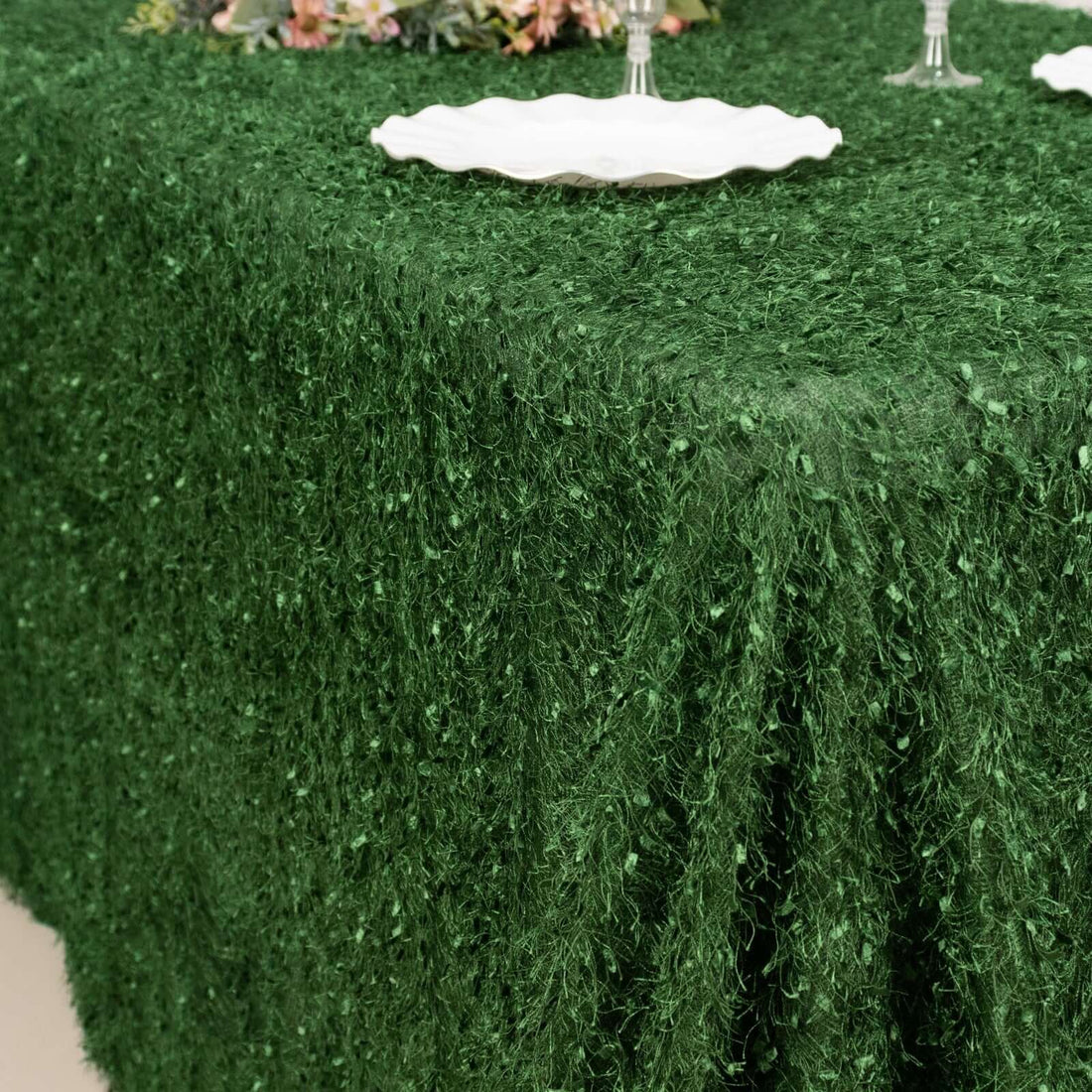 Green textured tablecloth draping elegantly over a table setting.