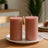 Pink pillar candles on a white plate in a cozy setting.