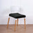 Black cushion on a modern white chair with wooden legs.