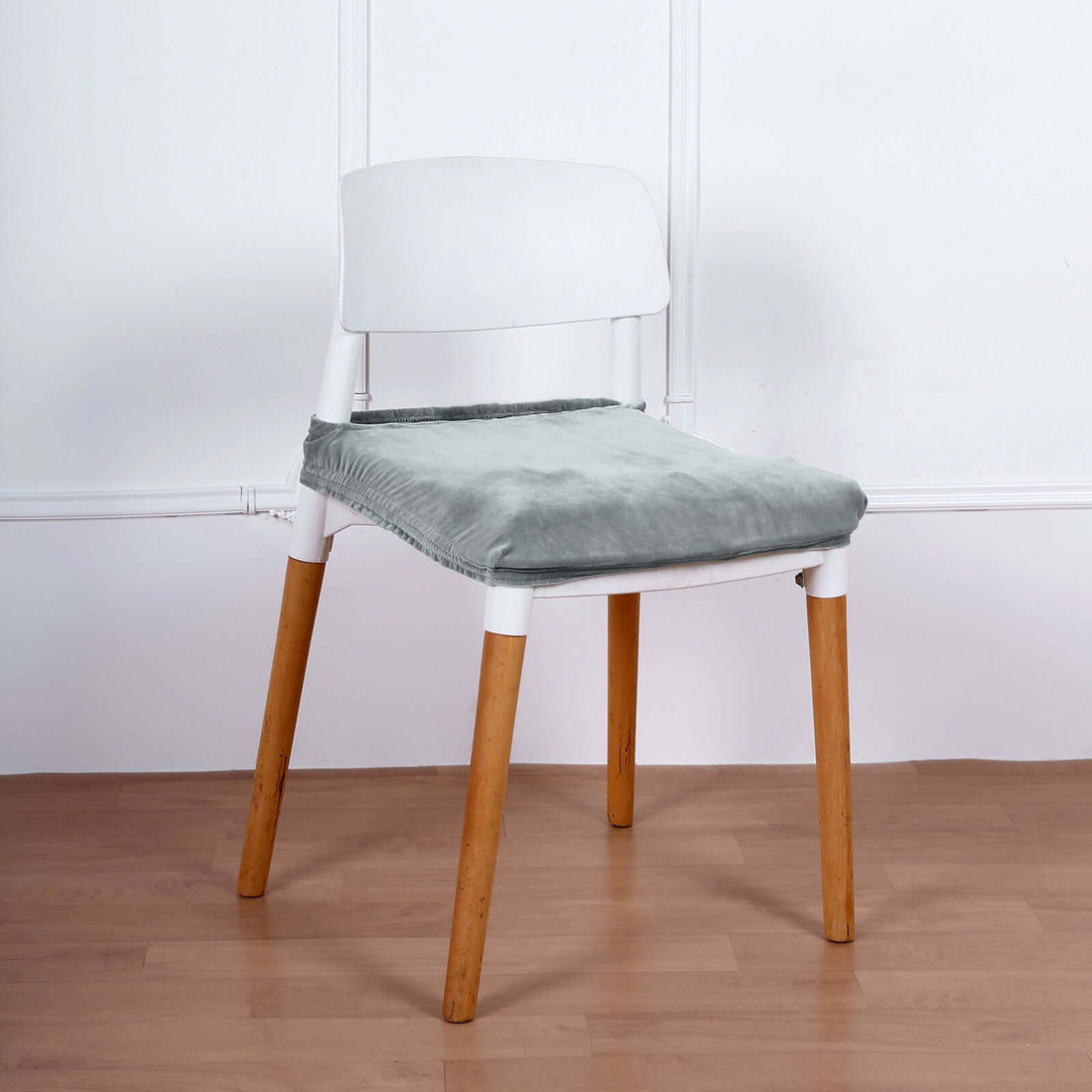 Modern chair with white backrest and wooden legs, featuring a soft green cushion.