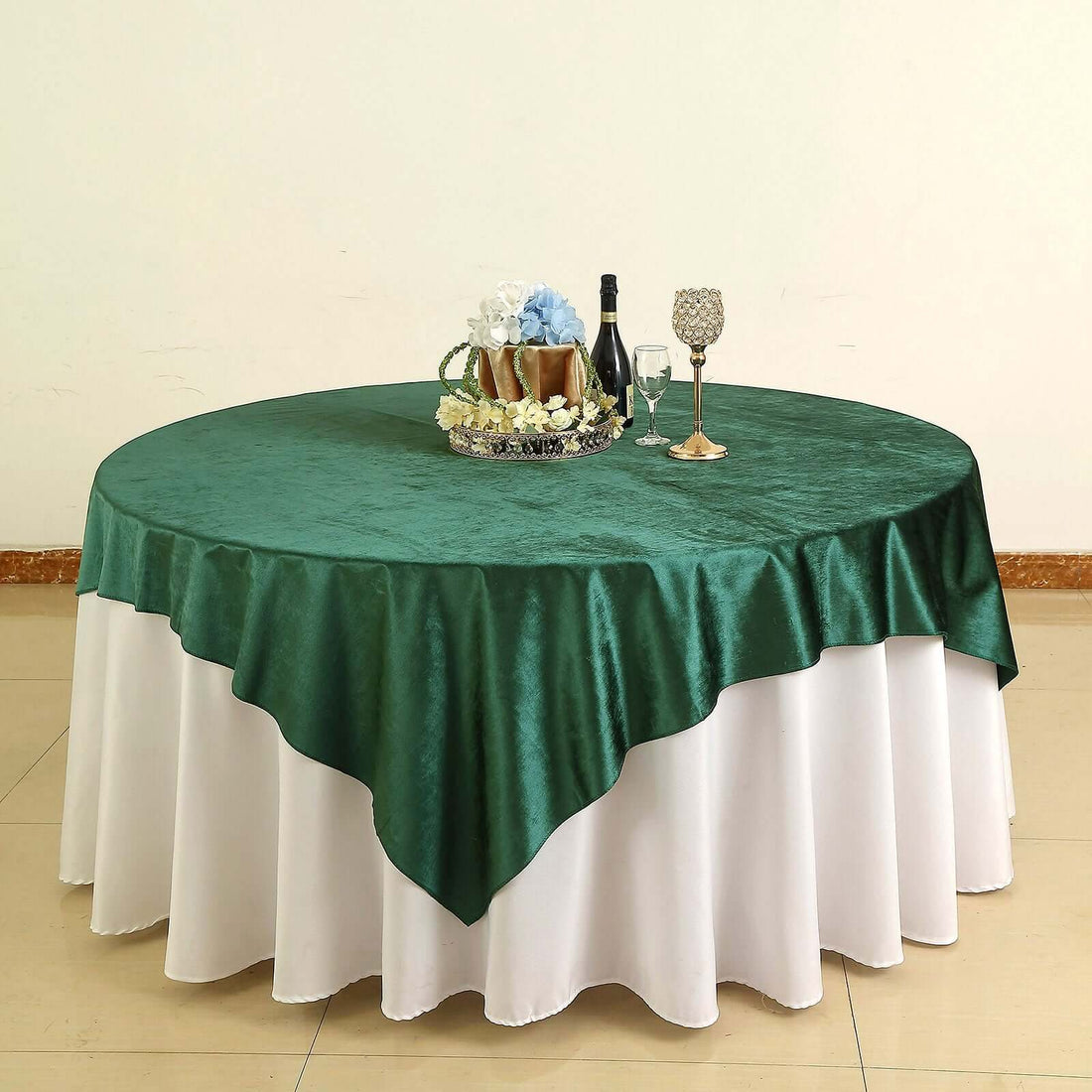 Green tablecloth draped over a round table with decorative items.