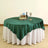 Green tablecloth draped over a round table with decorative items.