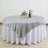 Silver tablecloth draped over a round table with decorative items.