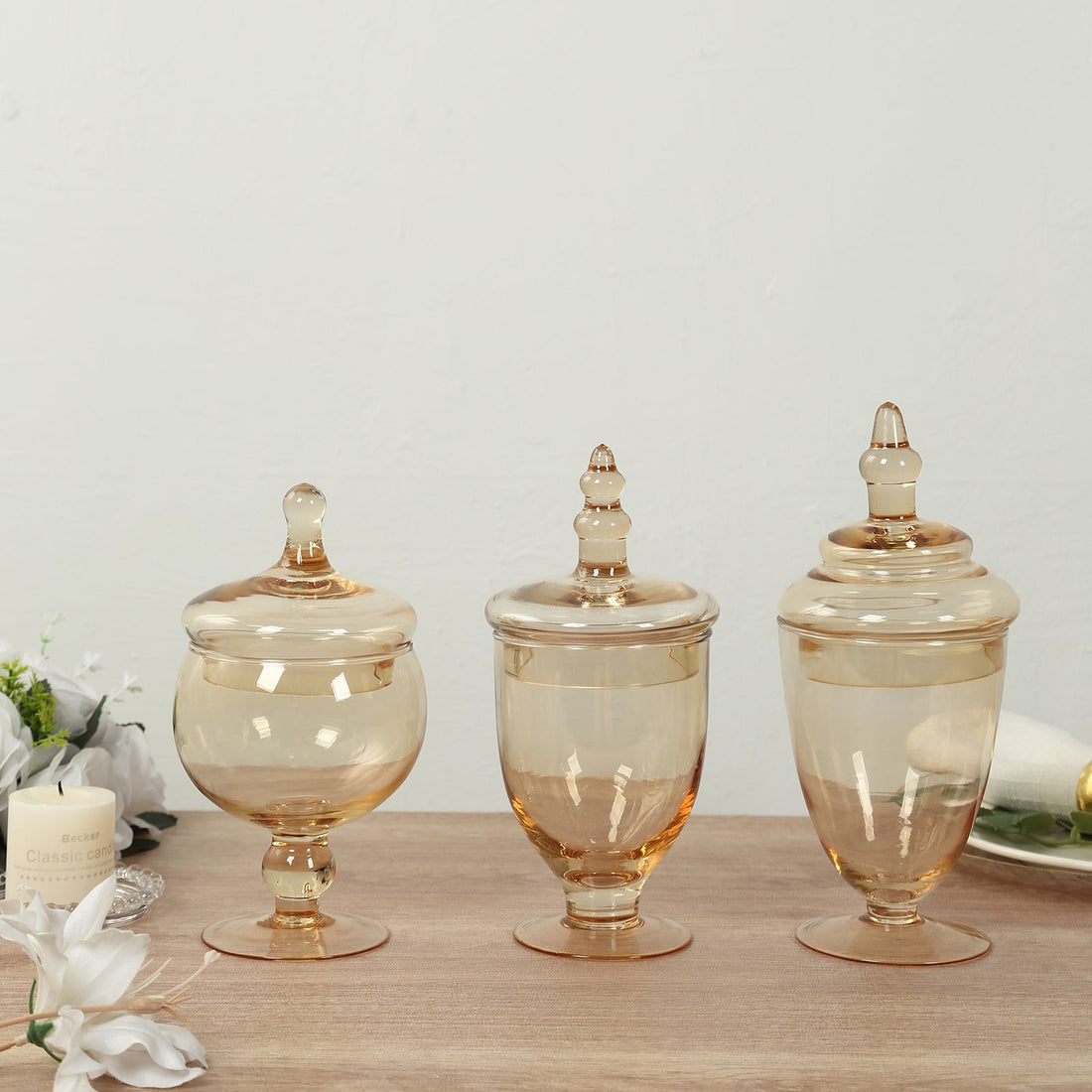 Set of three amber glass jars with lids on a wooden surface.