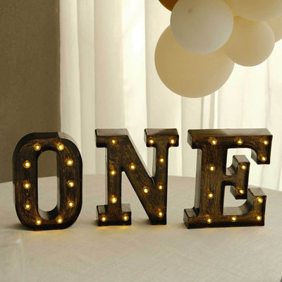 Lit marquee letters spelling ONE with warm fairy lights on a table