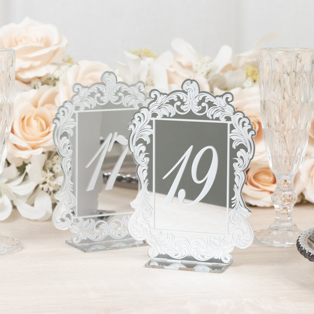 Elegant mirrored table number 19 with ornate design and floral backdrop.