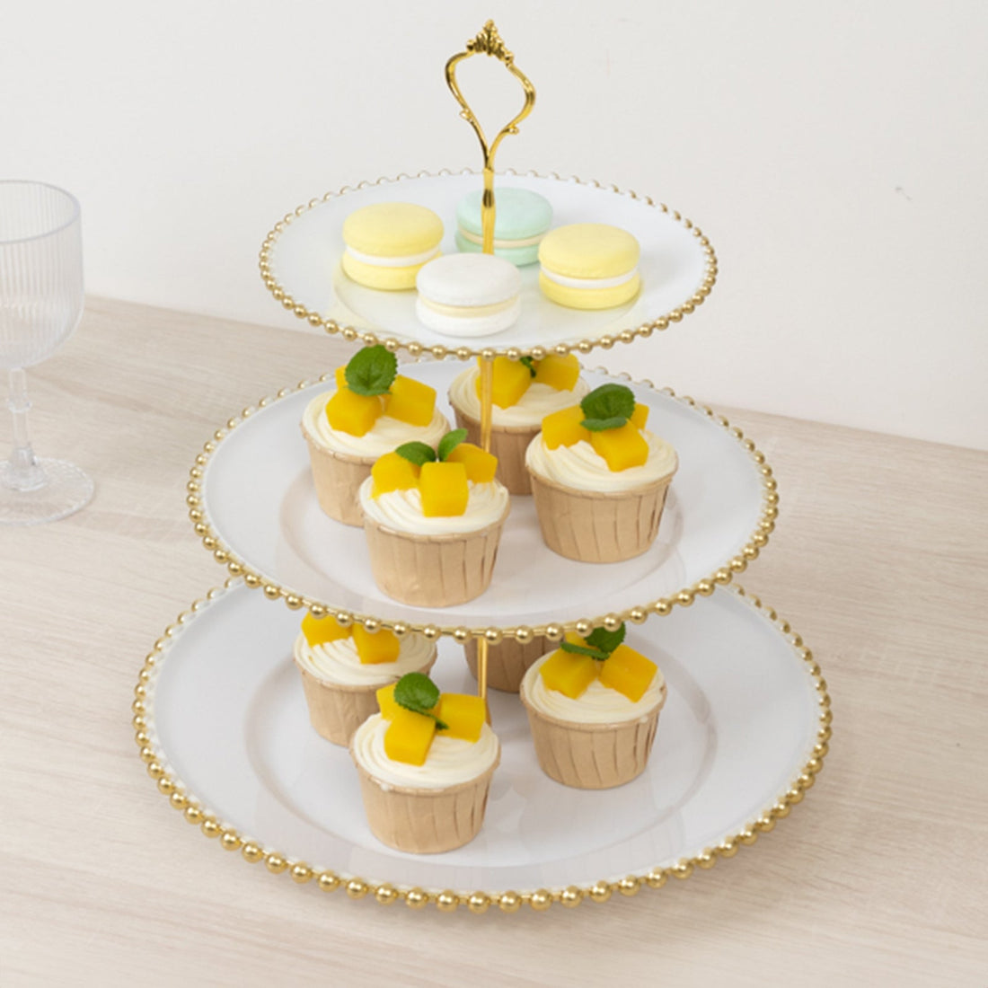 Three-tiered dessert stand with cupcakes and macarons displayed elegantly.