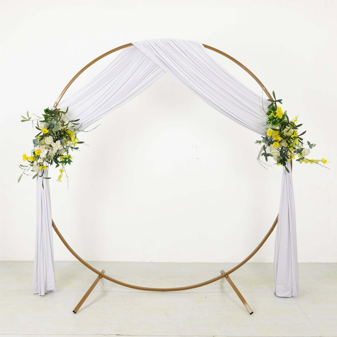 Gold circular wedding arch with white drapes and floral arrangements