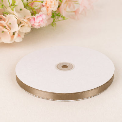 White and gold ribbon spool on pastel floral background
