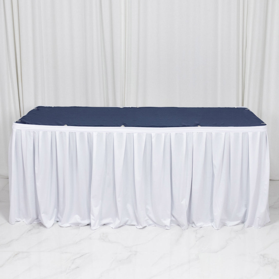 White banquet table with navy tablecloth and pleated skirt backdrop