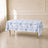 White tablecloth with blue French toile pattern on a table in a bright room.
