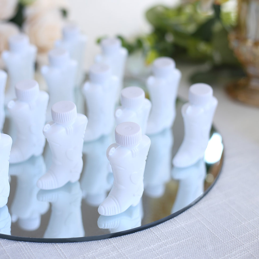 White boot-shaped bottles arranged on a mirrored surface.