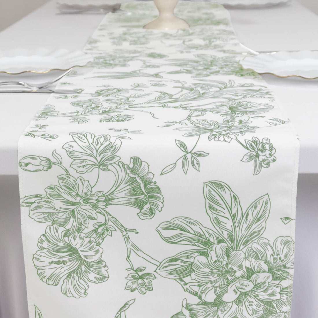 Green floral table runner on a white table setting.