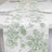 Green floral table runner on a white table setting.