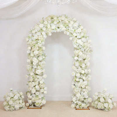 White floral wedding arch with roses and matching flower arrangements on a draped backdrop