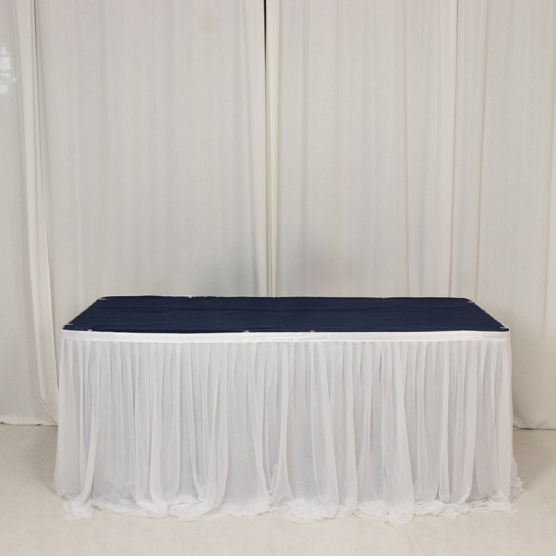 Navy table runner draped over a white tablecloth in a studio setting.