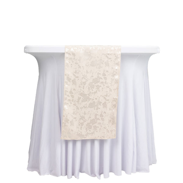White round cocktail table with ivory sequin table runner on draped linen tablecloth