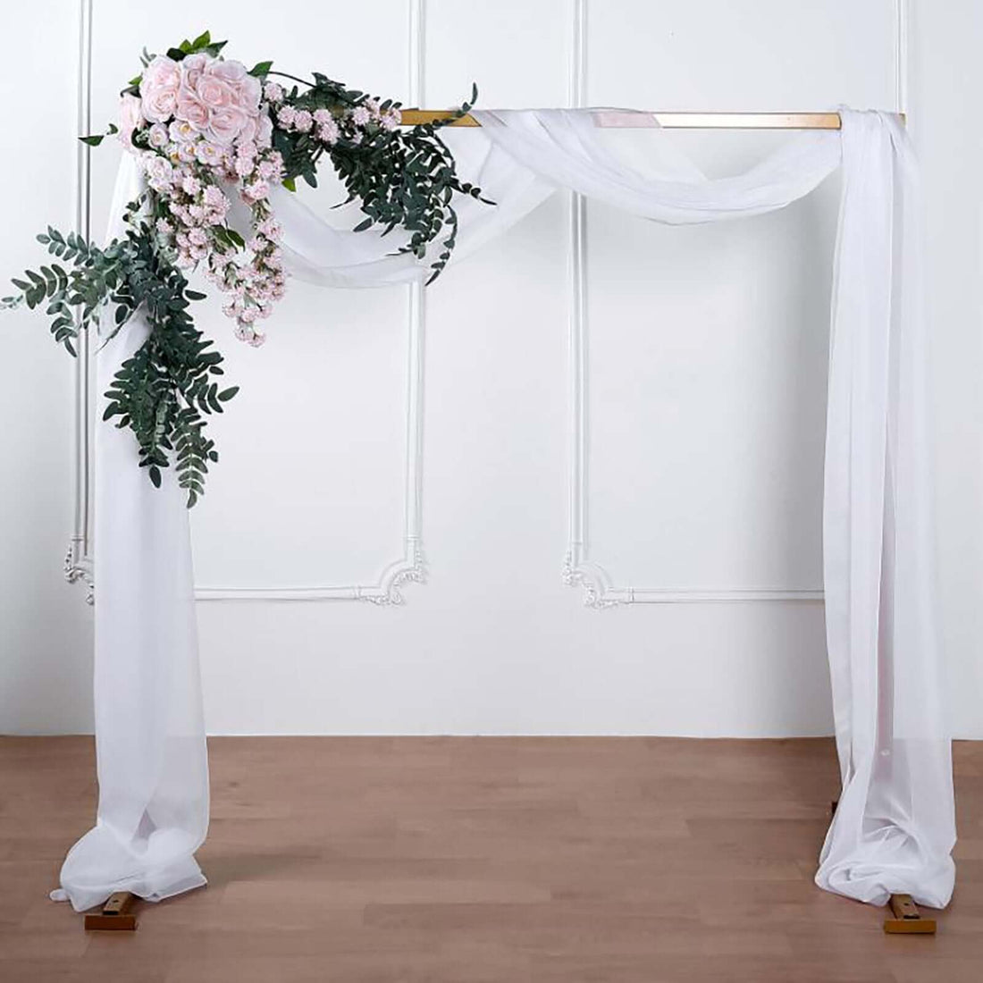 Wedding arch with floral arrangement and flowing fabric drapes