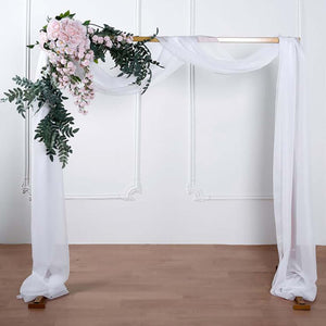 Wedding arch with floral arrangement and flowing fabric drapes