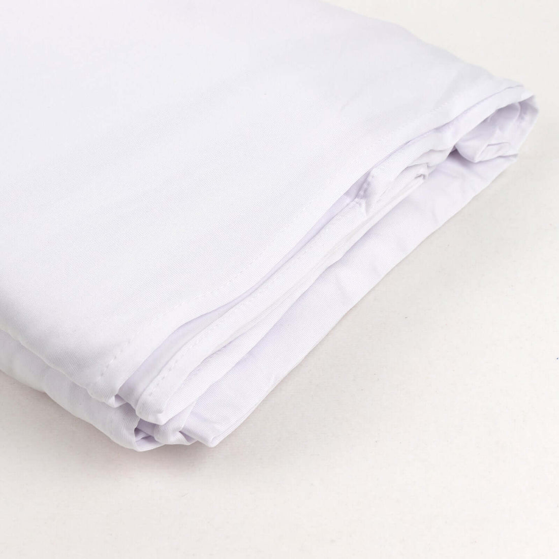 Folded white fabric sheet on a plain background.