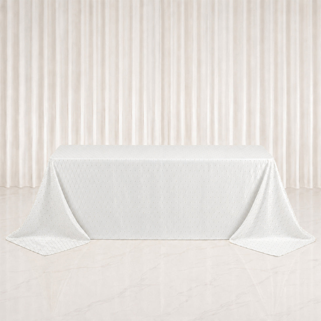 White tablecloth draped over rectangular table with elegant cream curtains