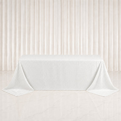White tablecloth draped over rectangular table with elegant cream curtains