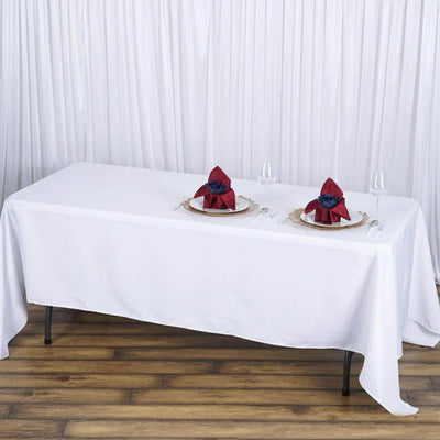 Elegant white table setup with red napkin decor and glassware.