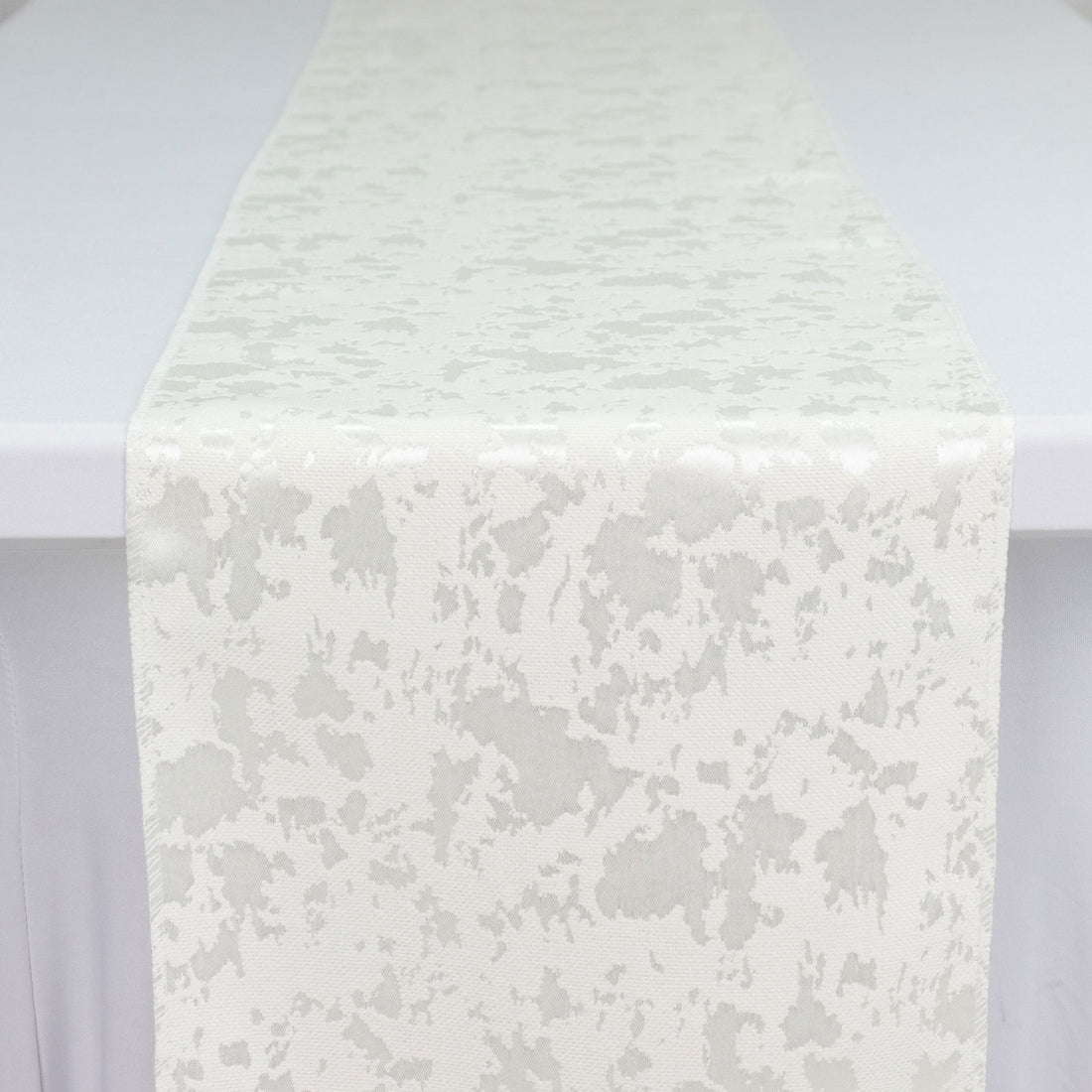 White textured fabric runner with subtle abstract pattern on a table
