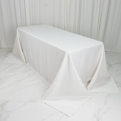 White textured tablecloth draped over rectangular table in minimal studio setting