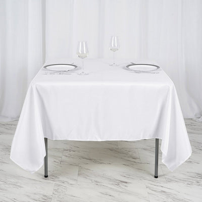 White tablecloth draped over a table set for two with glasses and plates.