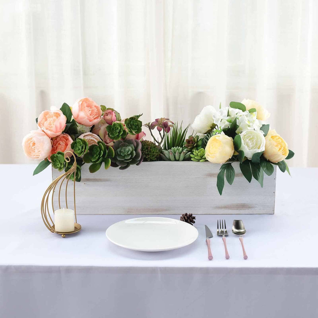 Decorative floral arrangement in a wooden planter with table setting.