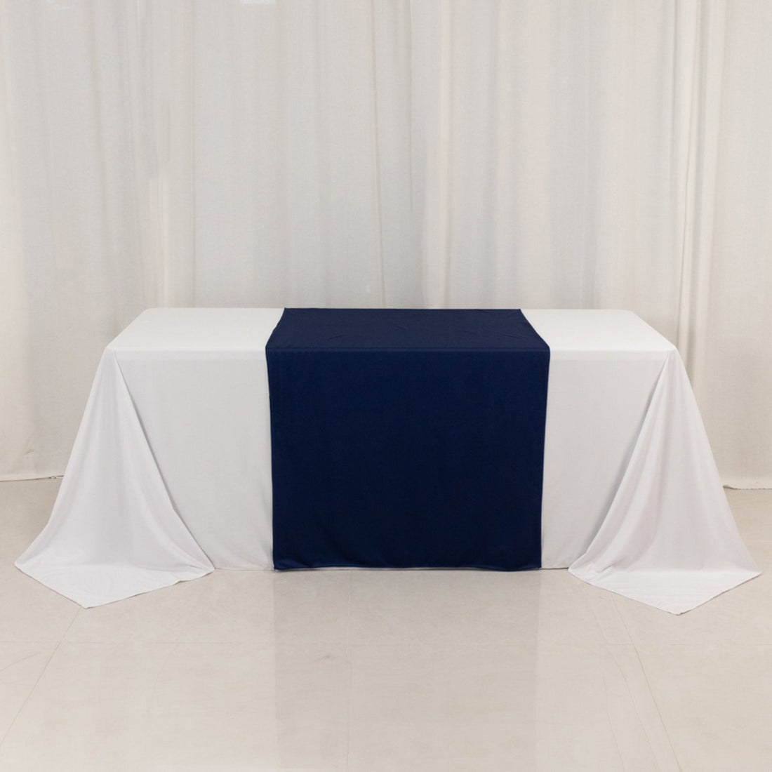 Navy table runner on a white table with draped white fabric