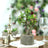Artificial bonsai tree in a textured pot on a dining table.