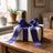 Wrapped gift box with purple ribbon bow on wooden table