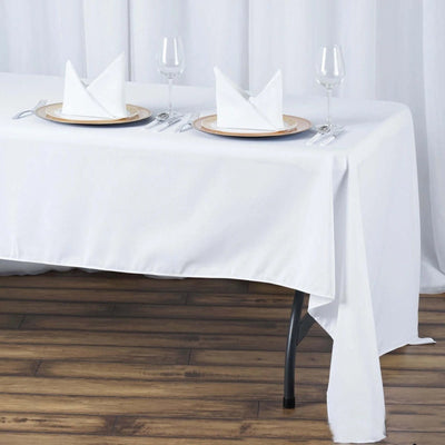 Elegant dining table setup with white tablecloth, plates, and folded napkins.