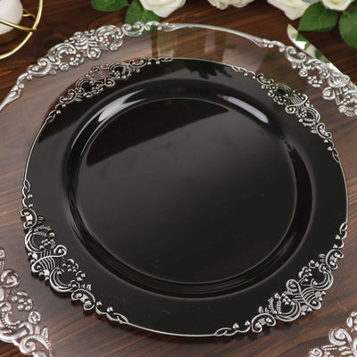 Black decorative plate with silver ornate design on a wooden surface.