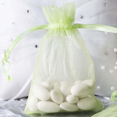 White candy-coated almonds in a green organza bag.